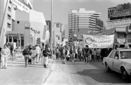 Protesters holding banners walking down a street. Toronto, 1988.
