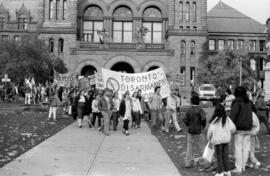 Protesters walking and holding banners  in front of the Ontario Legislative Building. Toronto, 1988.