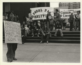 Group of people holding "Stop protecting employers," "Legislate equal pay for work of equal value...