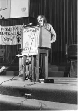 Heather MacNeil from SORWUC side view speaking at podium during the IWD 78, Convocation Hall