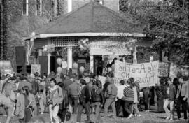A crowd standing in front of a gazebo, holding (L-R):  "Peace Please," "We Are The Future,"  and ...