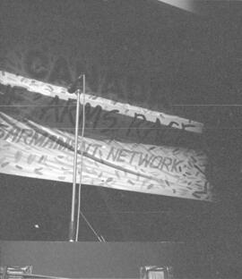 "Vote Canada Out Of The Arms Race, Toronto Disarmament Network" banner and a microphone on a stag...