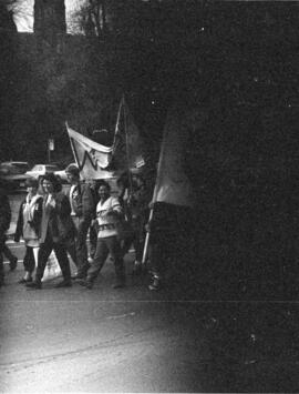 Small group of protesters hold signs in a street. Toronto, 1988.