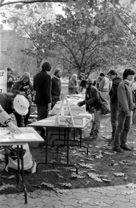 People signing forms at registration tables in a  park. Toronto, 1988.