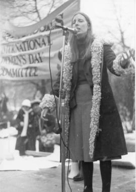 Margaret Cristal speaking into microphone onstage at International Women's Day (IWD) City Hall