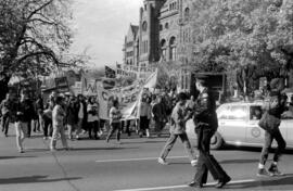 Front view of people protesting and holding banners in front of the Ontario Legislative Building....