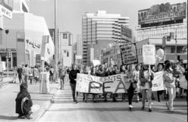 Protesters holding banners walking down a street. Toronto, 1988.