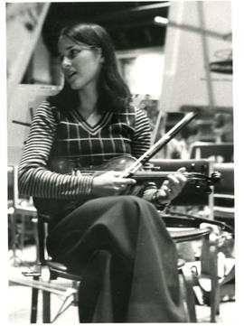 Unidentified woman sitting in front of a music stand and holding violin during a poetry reading r...