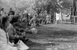 A group of people sitting on grass, looking at something to their right. TDN demonstration, Toron...