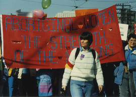 Woman in white stripped sweater and participants carrying a "Aboriginal Women, the Strength of Na...